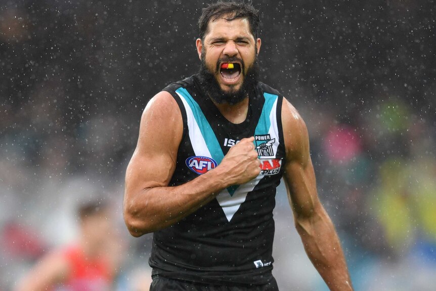 Patrick Ryder thumps his chest with his right fist while screaming. He's wearing a red, yellow and black mouthguard.