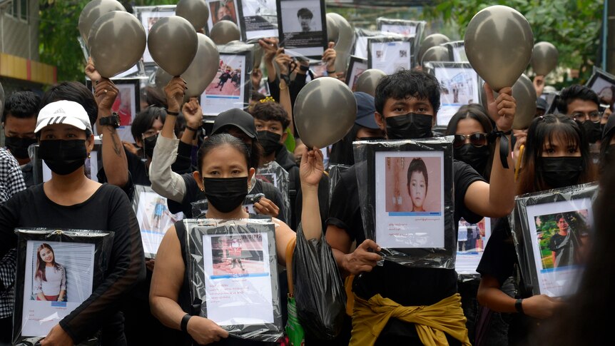 Anti-coup protesters holding pictures of those who died during a protest