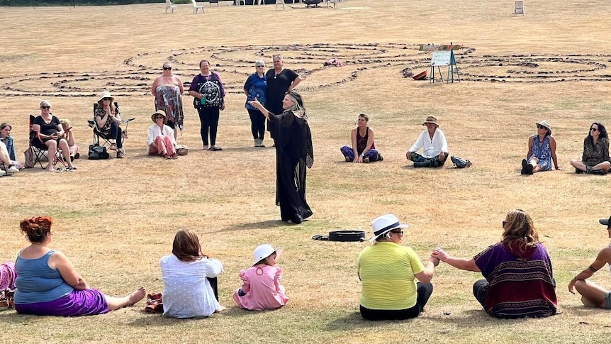 A circle of people at a ceremonial event in an open field.