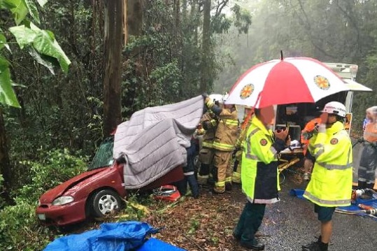 Emergency workers with a smashed car where a woman was trapped at Maleny on Queensland's Sunshine Coast.