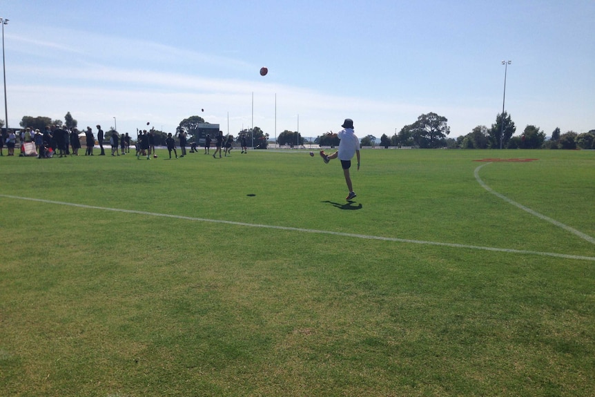 A boy kicks a football on Ted Summerton Reserve