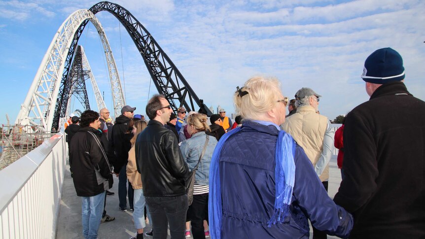 A crowd of people stands on Matagarup Bridge.