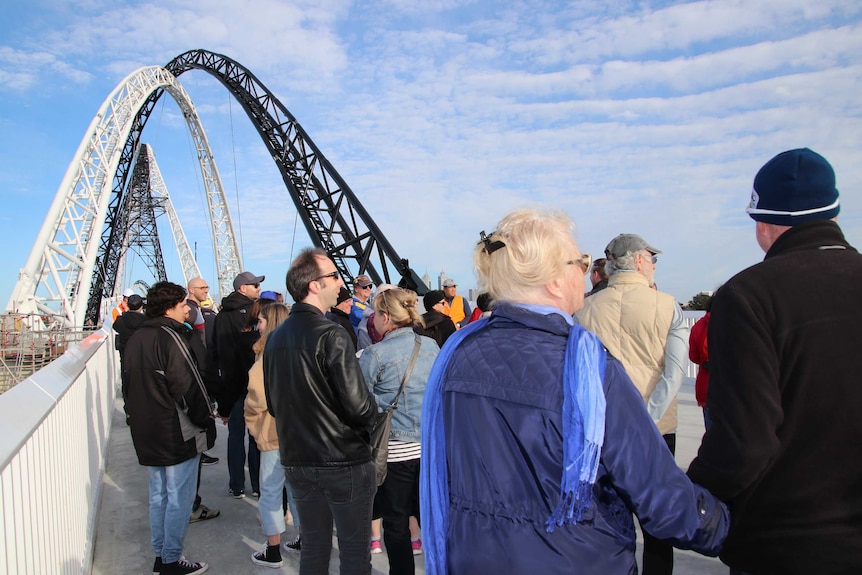 A crowd of people stands on Matagarup Bridge.