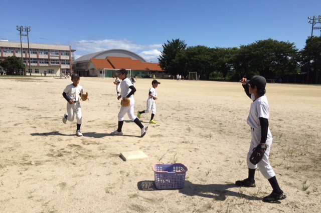 Young boys in uniforms practise throwing and catching