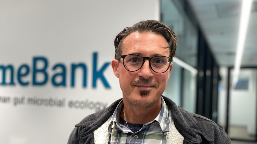A man stands infront of a blurry sign that says 'mebank'