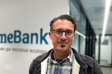 A man stands infront of a blurry sign that says 'mebank'