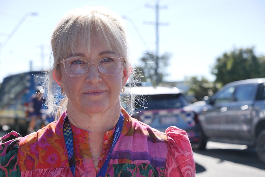 A blond woman with glasses and a police lanyard