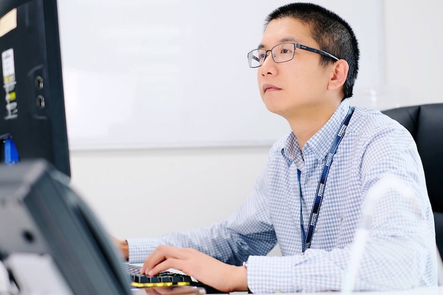 A man in a strip shirt uses a computer. 