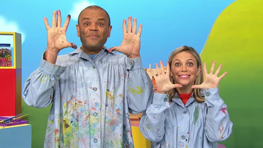 Luke and Rachael covered in paint holding up their hands