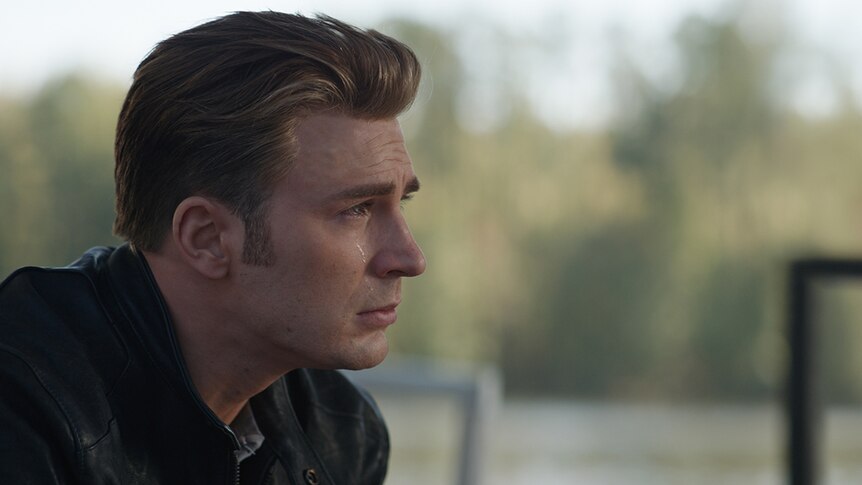 Colour close-up still of Chris Evans sitting outdoors and crying in 2019 film Avengers: Endgame.