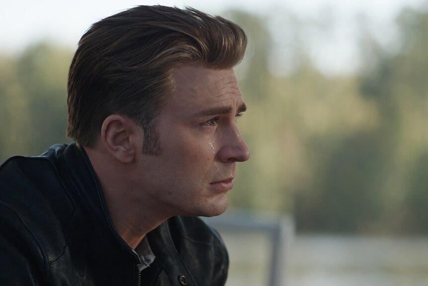 Colour close-up still of Chris Evans sitting outdoors and crying in 2019 film Avengers: Endgame.