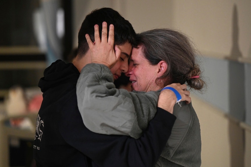 A woman and a man hugging, crying. 