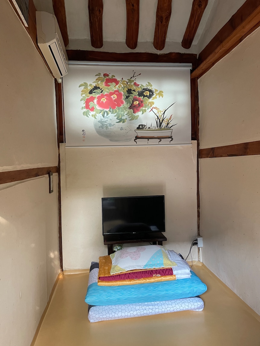 A single room, complete with a folded mattress, in a Hanok guesthouse.