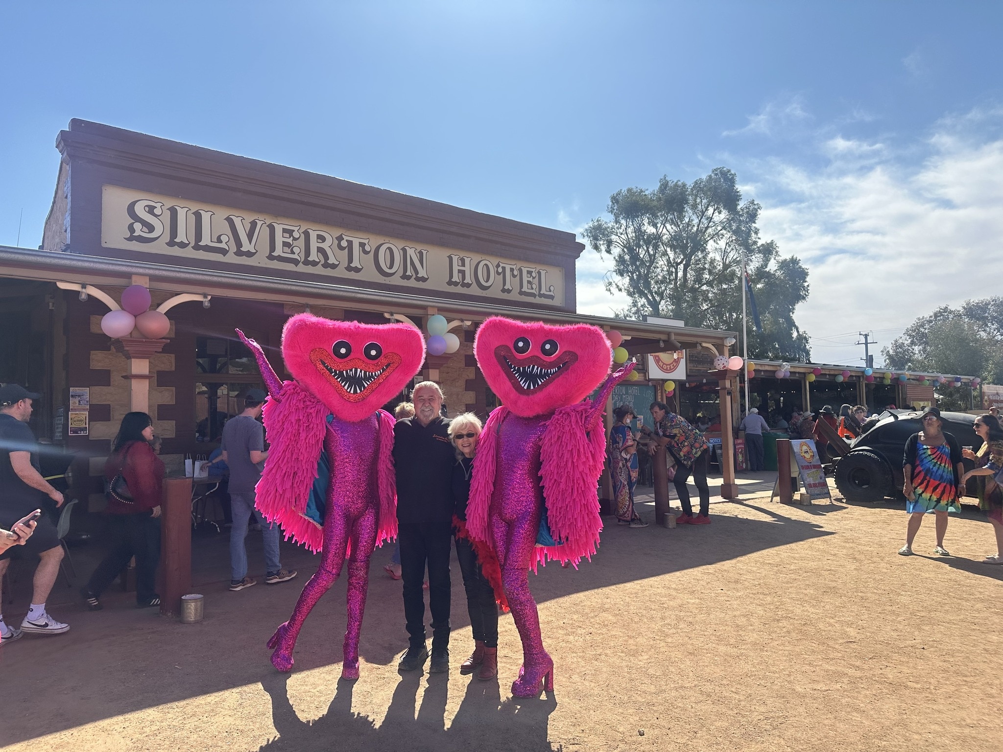 Dos personas vestidas de negro se encuentran afuera del pub Silverton con otras dos vestidas de rosa y con máscaras.