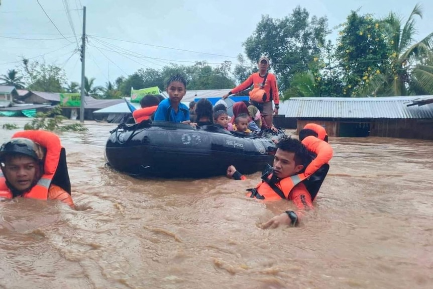 Children are rescued from flooding by a crew with a dinghy.