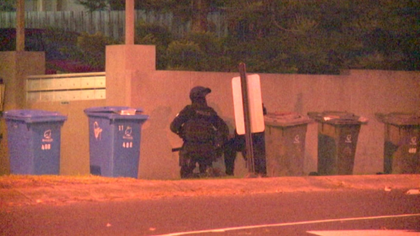 Police crouch near a building in Brighton