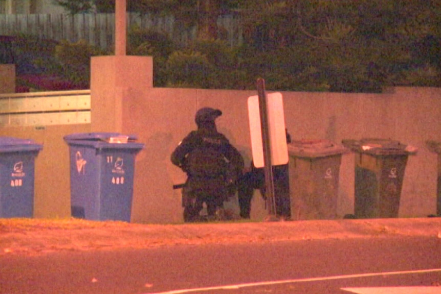 Police crouch near a building in Brighton