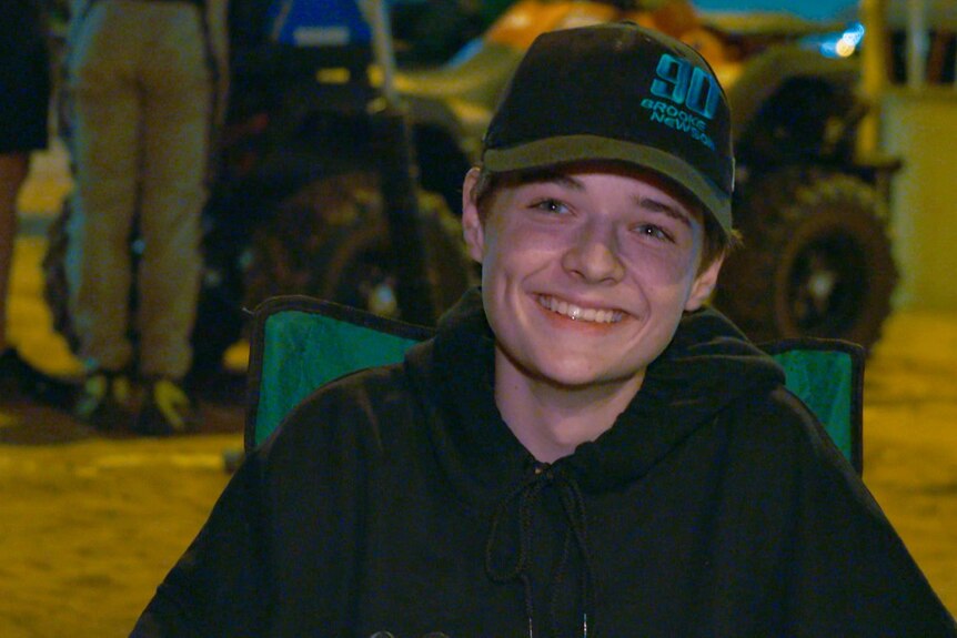 A boy sitting in a camp chair smiling