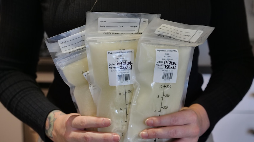 A close up of a woman holding three bags of frozen breastmilk