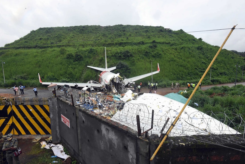 Officials stand by the debris of a passenger plane which has split into two pieces.