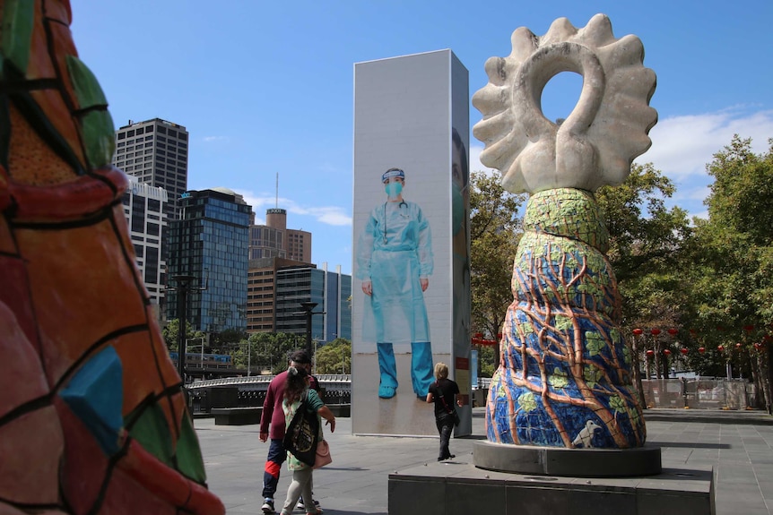 A large photo of an infectious diseases nurse in PPE between two other pieces of artwork.