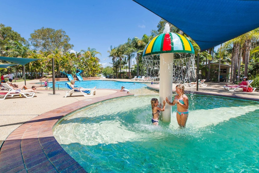 Girls playing under water fountain at resort pool
