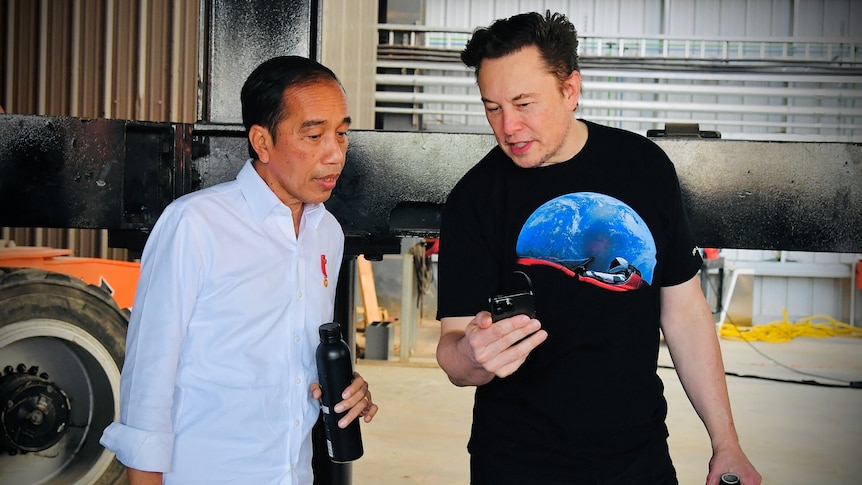 Indonesian President Joko Widodo talks with Elon Musk while looking at a smart phone