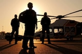 Three CareFlight workers stand in front of a helicopter at sunset.