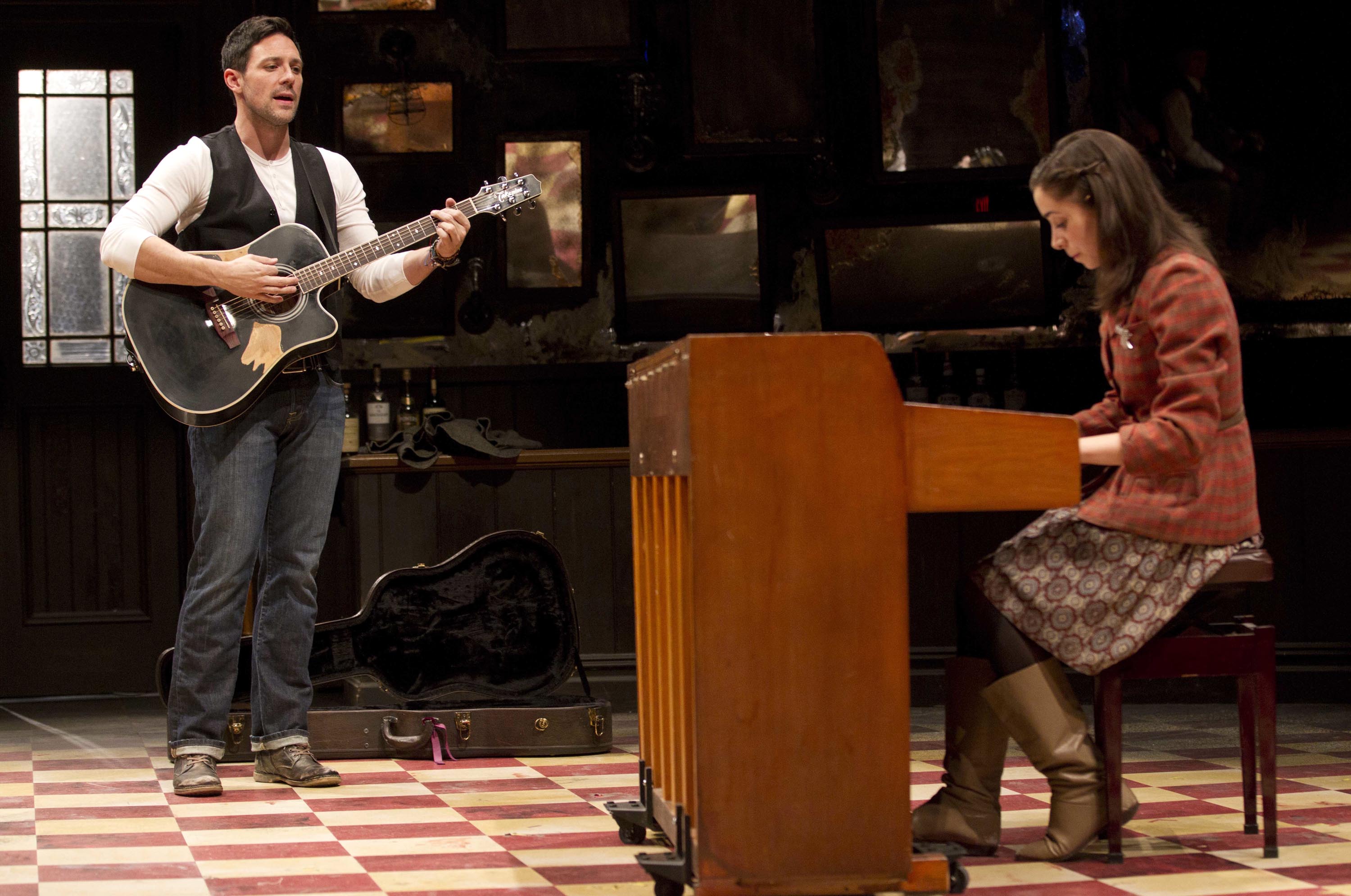 Steve Kazee playing guitar and Cristin Miloti at the piano on stage in the Broadway musical Once