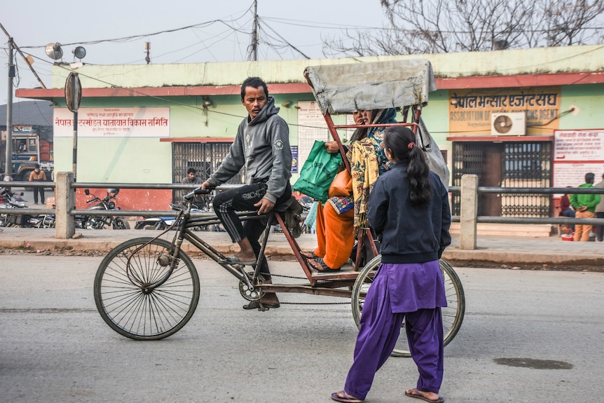 A woman stops a group of people at the Nepal-India border to talk to them.