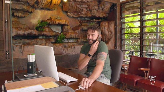 Man in office with back wall filled with rocks and ferns growing in it