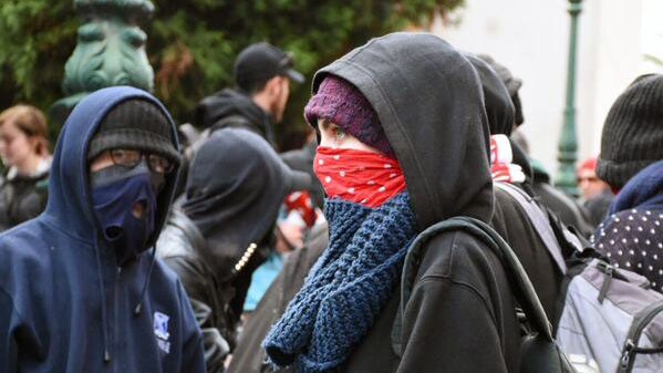 Anti-racism protesters cover their faces ahead of rally over new mosque at Bendigo