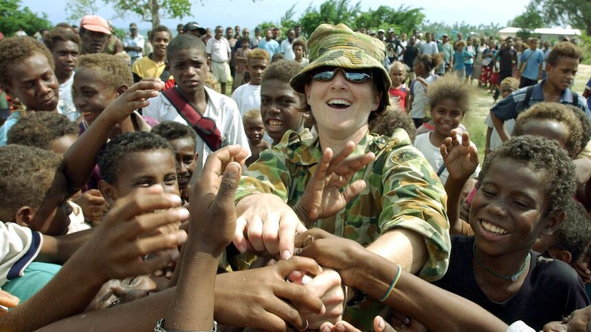 An unidentified Australian soldier distributes candy to village children in Auki, Solomon Islands, in 2003.