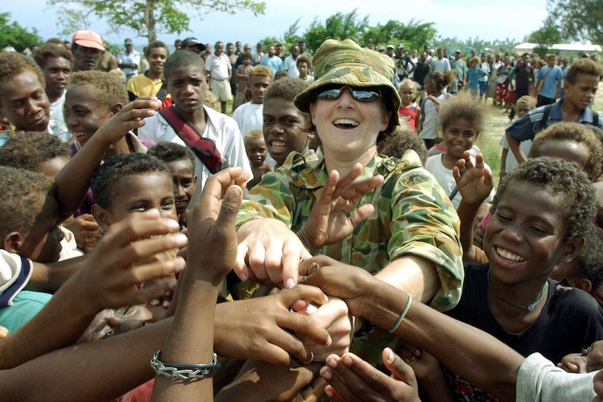 An unidentified Australian soldier distributes candy to village children in Auki, Solomon Islands, in 2003.