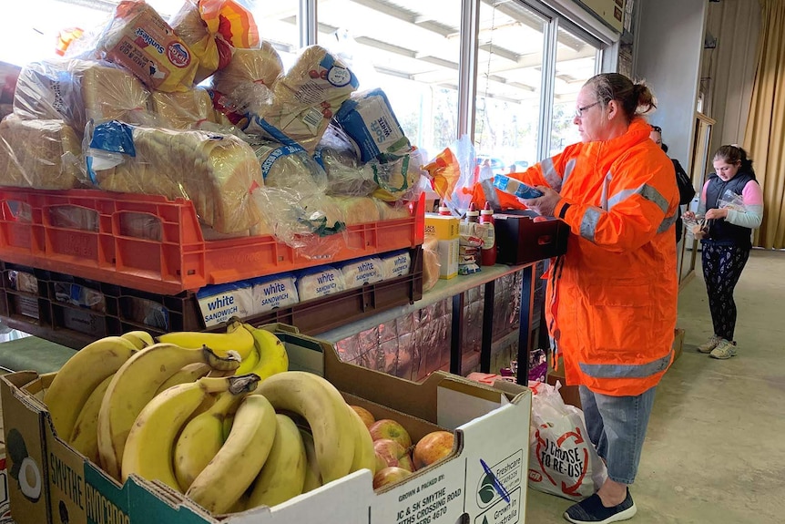 People examining stacks of food on tables in a warehouse