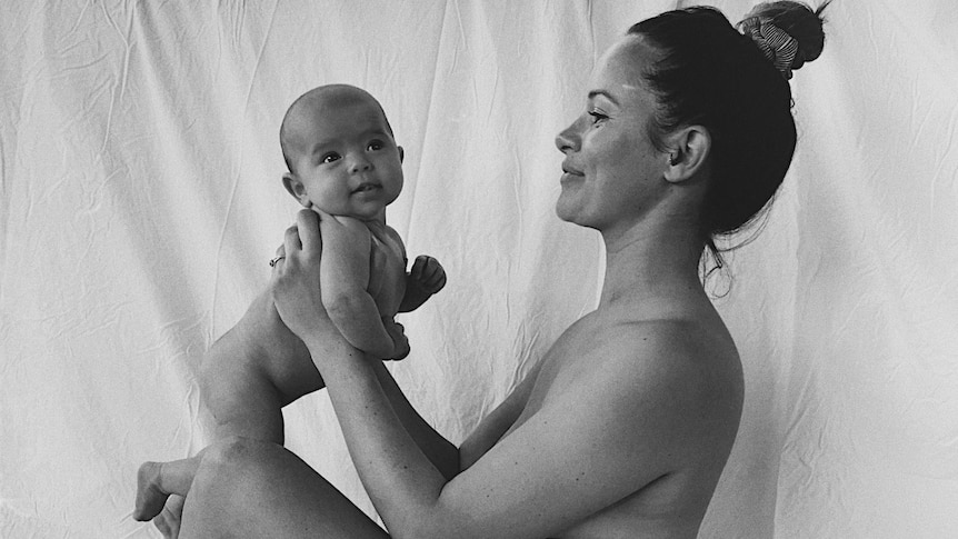 A naked Jayde Couldwell holds one of her children.
