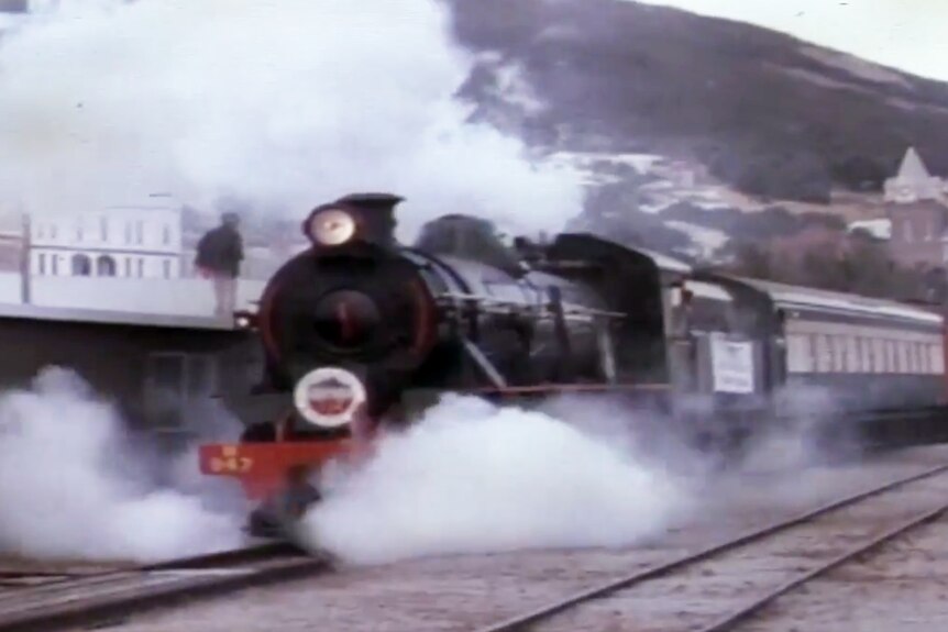 A steam train leaves the station.
