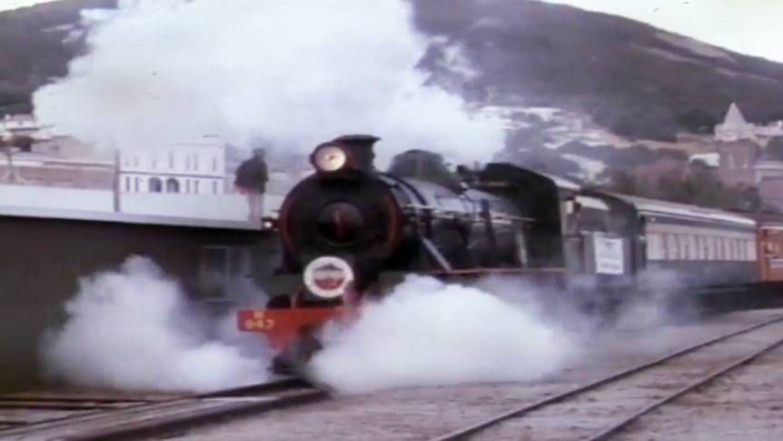 A steam train leaves the station.