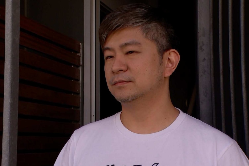 A man stands in the front doorway of his home