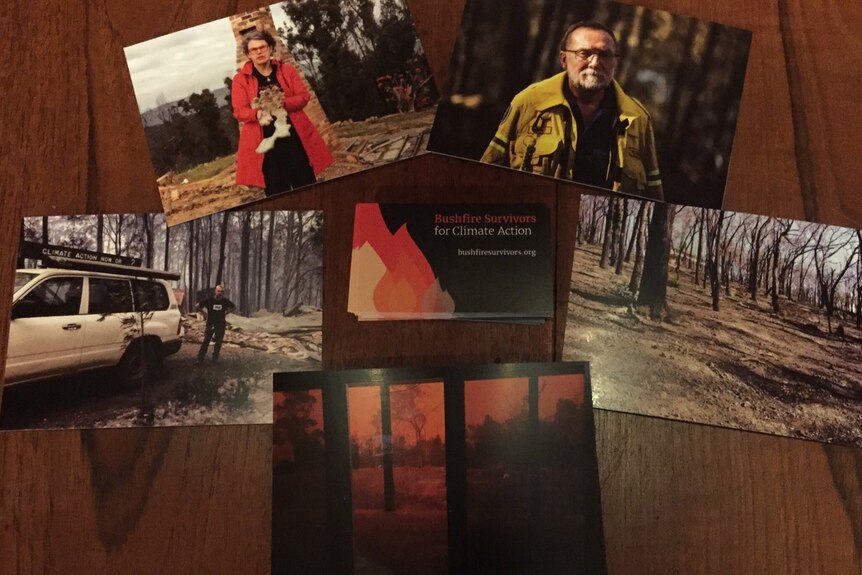 Postcards lay on a table: one shows a woman in front of a burnt home, and another shows a firefighter in burnt bushland.