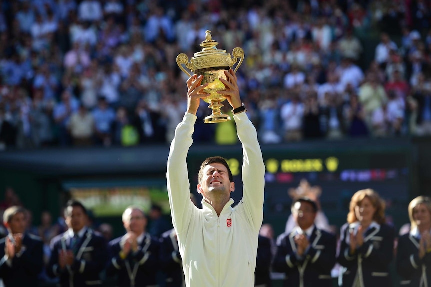 Novak Djokovic holds the winner's trophy after beating Roger Federer in the men's final at Wimbledon.