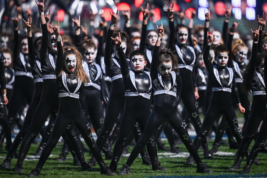 Kids dressed as Kiss band members, raising their arms in rock signs.