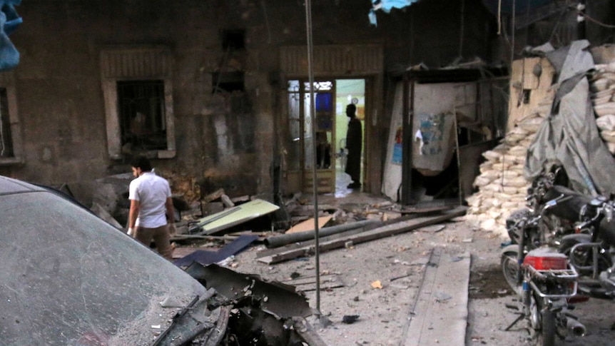 Medics inspect the damage outside a field hospital after an airstrike in Aleppo - they are surrounded by rubble and ruins.