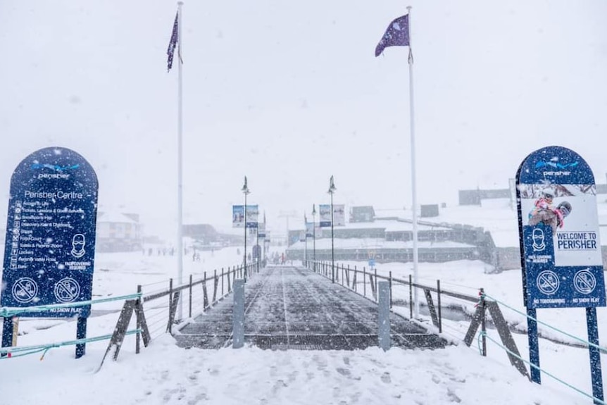 Snow falls and blankets Perisher ski resort entrance looking towards the main ticket area.