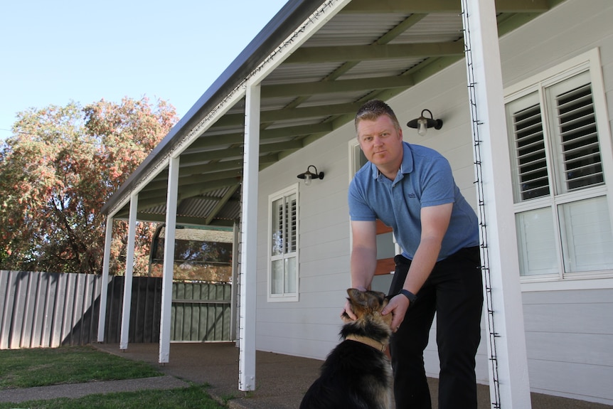 L'homme devant la maison tient le chien