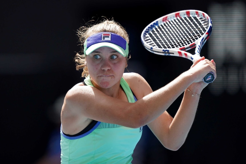 A female tennis player prepares to play a double-fisted backhand at the Australian Open.