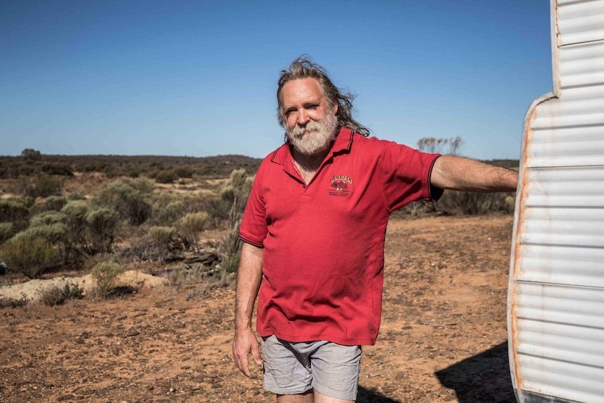A man standing in front of a caravan in outback Western Australia