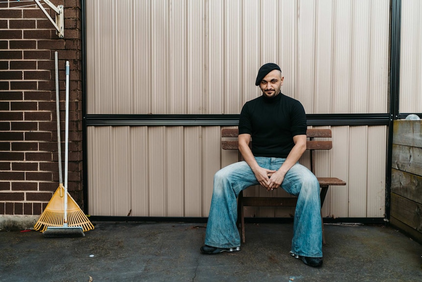 The Lebs author Michael Mohammed Ahmad sitting on a wooden bench in his backyard.