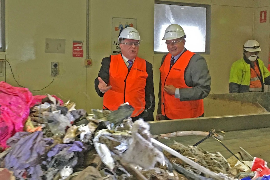Environment Minister Ian Hunter and SUEZ waste firm executive director Emmanuel Vivant look at a recycling conveyer belt
