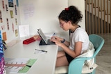 12-year-old Sophia sits at a study desk, typing on a device. She's wearing glasses and has her curly, dark hair in a ponytail.